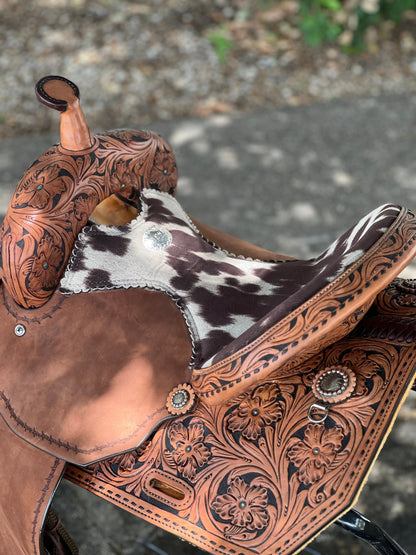 Close-up of a brown leather saddle with intricate patterns on a blurred background
